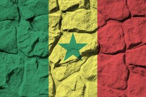 Senegal flag depicted in paint colors on old stone wall closeup. Textured banner on rock wall background photo