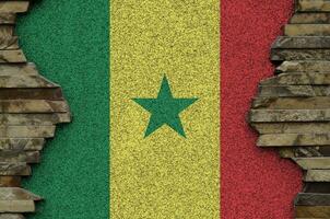 Senegal flag depicted in paint colors on old stone wall closeup. Textured banner on rock wall background photo