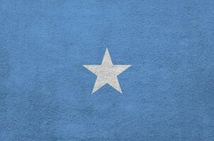 Somalia flag depicted in bright paint colors on old relief plastering wall. Textured banner on rough background photo