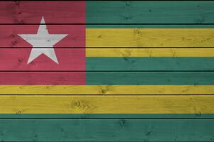 Togo flag depicted in bright paint colors on old wooden wall. Textured banner on rough background photo