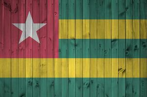 Togo flag depicted in bright paint colors on old wooden wall. Textured banner on rough background photo