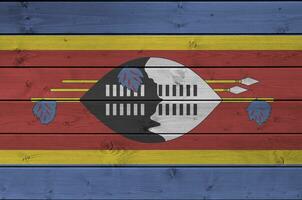 Swaziland flag depicted in bright paint colors on old wooden wall. Textured banner on rough background photo