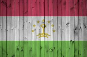Tajikistan flag depicted in bright paint colors on old wooden wall. Textured banner on rough background photo