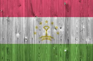 Tajikistan flag depicted in bright paint colors on old wooden wall. Textured banner on rough background photo