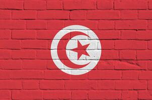 Tunisia flag depicted in paint colors on old brick wall. Textured banner on big brick wall masonry background photo