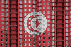 Tunisia flag depicted in paint colors on multi-storey residental building under construction. Textured banner on brick wall background photo