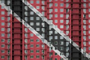 Trinidad and Tobago flag depicted in paint colors on multi-storey residental building under construction. Textured banner on brick wall background photo