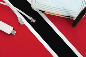Trinidad and Tobago flag depicted on table with internet rj45 cable, wireless usb wifi adapter and router. Internet connection concept photo