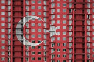 Turkey flag depicted in paint colors on multi-storey residental building under construction. Textured banner on brick wall background photo