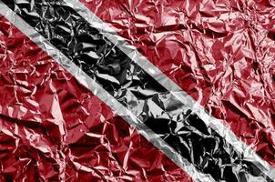 Trinidad and Tobago flag depicted in paint colors on shiny crumpled aluminium foil closeup. Textured banner on rough background photo