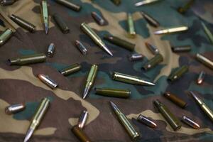 Many rifle bullets and cartridges on dark camouflage background photo