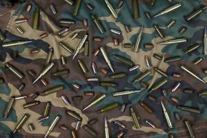 Many rifle bullets and cartridges on dark camouflage background photo