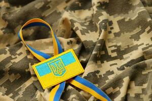 tela de camuflaje militar con bandera ucraniana en chevron uniforme foto