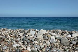 Bank of pebbles with the sea and beach in the background photo