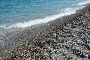 Bank of pebbles with the sea and beach in the background photo