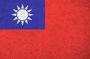 Taiwan flag depicted in bright paint colors on old relief plastering wall. Textured banner on rough background photo
