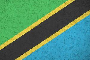 Tanzania flag depicted in bright paint colors on old relief plastering wall. Textured banner on rough background photo