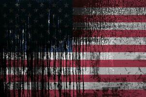 United States of America flag depicted in paint colors on old and dirty oil barrel wall closeup. Textured banner on rough background photo