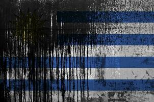 Uruguay flag depicted in paint colors on old and dirty oil barrel wall closeup. Textured banner on rough background photo