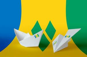 Saint Vincent and the Grenadines flag depicted on paper origami airplane and boat. Handmade arts concept photo