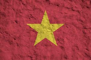 Vietnam flag depicted in bright paint colors on old relief plastering wall. Textured banner on rough background photo