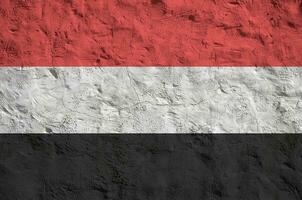 Yemen flag depicted in bright paint colors on old relief plastering wall. Textured banner on rough background photo