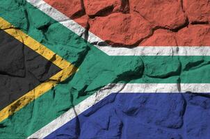 South Africa flag depicted in paint colors on old stone wall closeup. Textured banner on rock wall background photo