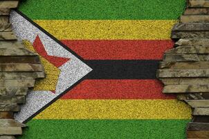 Zimbabwe flag depicted in paint colors on old stone wall closeup. Textured banner on rock wall background photo