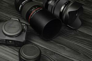 Canon EOS R photocamera and mount adapter EF - EOS R with Canon 105mm f2.8 and Sigma 24-105 f4 Art lenses on black wooden table photo