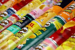 Pringles variety of flavors. Many cardboard tube cans with Pringles potato chips. Pringles is a brand of potato snack chips owned by the Kellogg Company photo