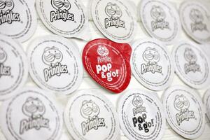 Pringles logo on paper membranes on white wooden table. Pringles is a brand of potato snack chips owned by Kellogg Company photo