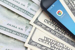 Smartphone screen with Google chrome app and lot of hundred dollar bills. Business and social networking concept photo