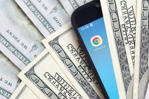 Smartphone screen with Google chrome app and lot of hundred dollar bills. Business and social networking concept photo