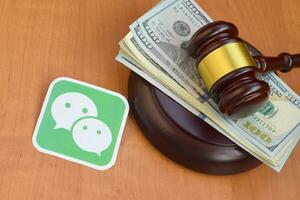 Wechat paper logo lies with judge gavel and hundred dollar bills. Entertainment lawsuit concept photo