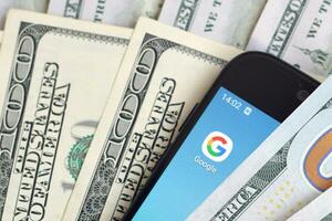 Smartphone screen with Google app and lot of hundred dollar bills. Business and social networking concept photo