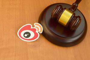 Weibo paper logo lies with wooden judge gavel. Entertainment lawsuit concept photo