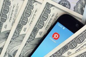 Smartphone screen with Pinterest app and lot of hundred dollar bills. Business and social networking concept photo