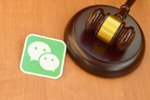 Wechat paper logo lies with wooden judge gavel. Entertainment lawsuit concept photo