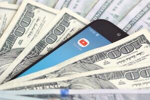 Smartphone screen with Youtube app and lot of hundred dollar bills. Business and social networking concept photo