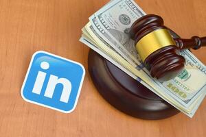 Linkedin paper logo lies with judge gavel and hundred dollar bills. Entertainment lawsuit concept photo