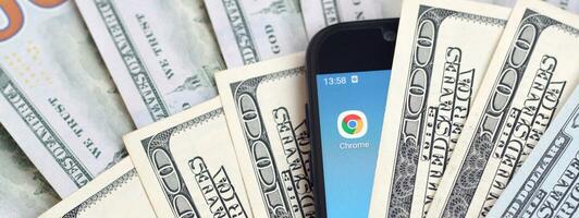 Smartphone screen with Google chrome app and lot of hundred dollar bills. Business and social networking concept photo