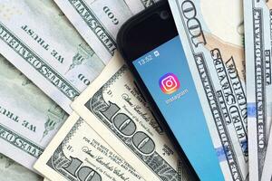 Smartphone screen with Instagram app and lot of hundred dollar bills. Business and social networking concept photo