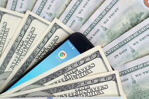 Smartphone screen with Google chrome app and lot of hundred dollar bills. Business and social networking concept photo