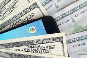 Smartphone screen with Google chrome app and lot of hundred dollar bills. Business and social networking concept photo