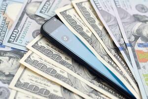 Smartphone screen with Tiktok app and lot of hundred dollar bills. Business and social networking concept photo