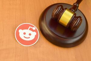 Reddit paper logo lies with wooden judge gavel. Entertainment lawsuit concept photo
