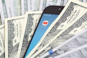 Smartphone screen with Youtube app and lot of hundred dollar bills. Business and social networking concept photo