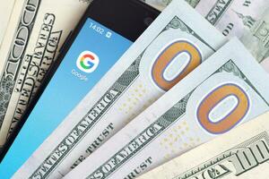 Smartphone screen with Google app and lot of hundred dollar bills. Business and social networking concept photo