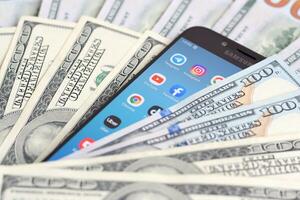 Smartphone screen with many popular apps and lot of hundred dollar bills. Business and social networking concept photo