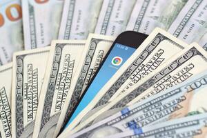 Smartphone screen with Google chrome app and lot of hundred dollar bills. Business and social networking concept photo